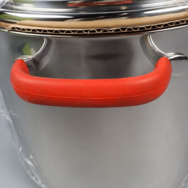 Närbild på rött handtag av grytan i rostfritt stål