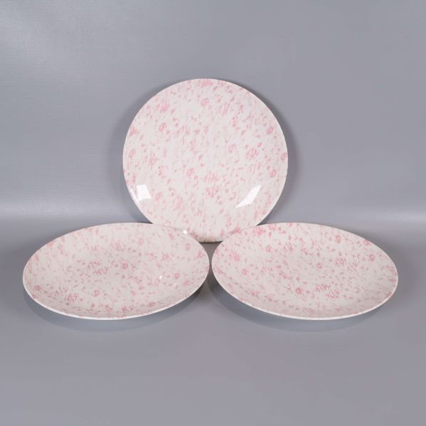 Tre assietter i rosa och vitt porslin, utplacerade på rad