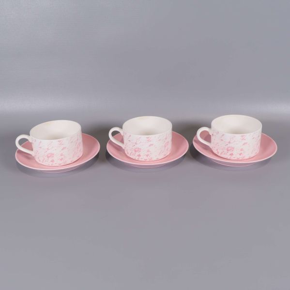 Tre kaffekoppar med rosa fat placerade i rad