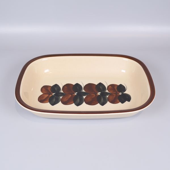 Rektangulär form med brunt och svart bladmönster mot beige botten