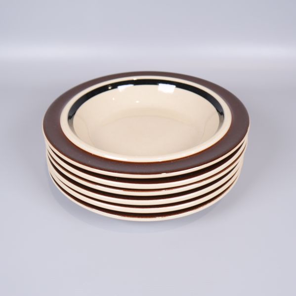 Staplade gräddvita tallrikar med bred brun kant