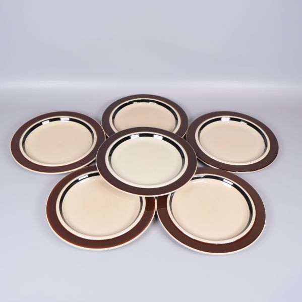 Sex tallrikar med brun bred kant arrangerade i cirkel