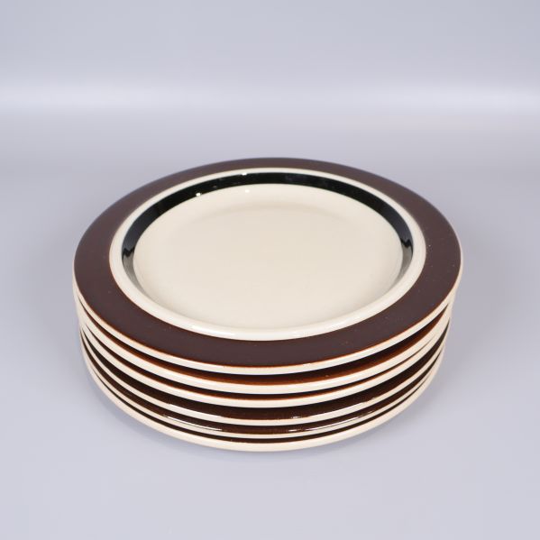 Hög med sex staplade tallrikar med brun kant
