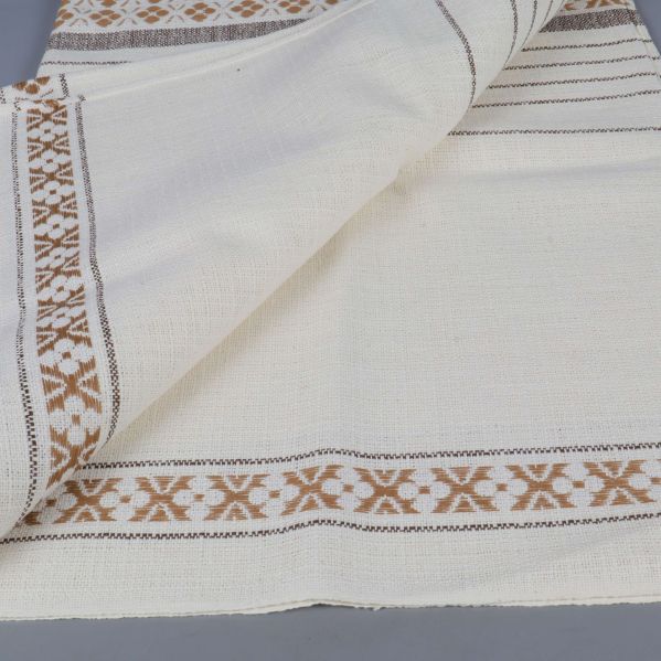 Närbild på mönstrat tyg av bordsduk i vitt och brunt