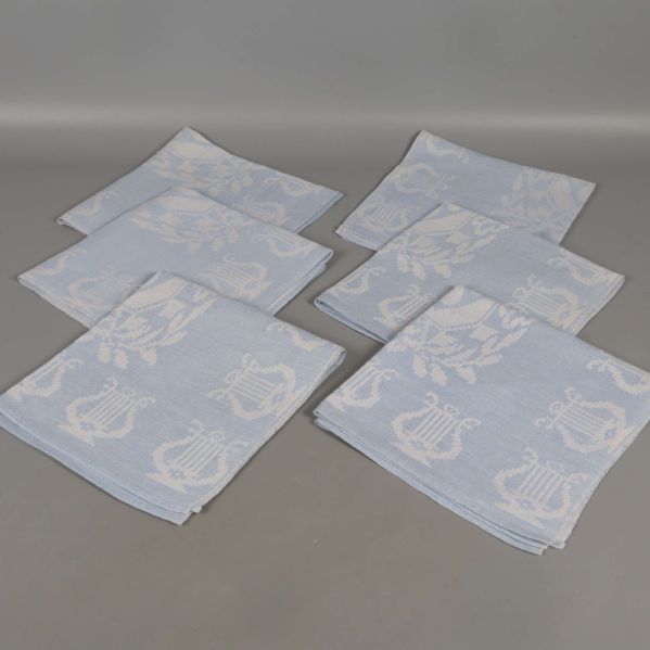 Sex ljusblå och vita linneservetter utlagda på ett bord