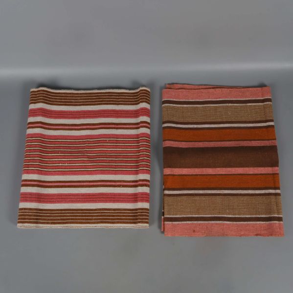 Två vikta randiga dukar med rosa och bruna toner