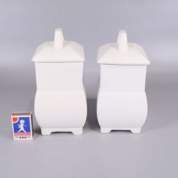 Baksidan av två vita burkar med tändsticksask för storleksjämförelse