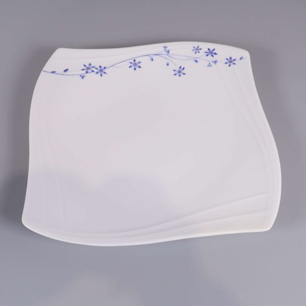 Närbild på en fyrkantig vit tallrik med blå blommor