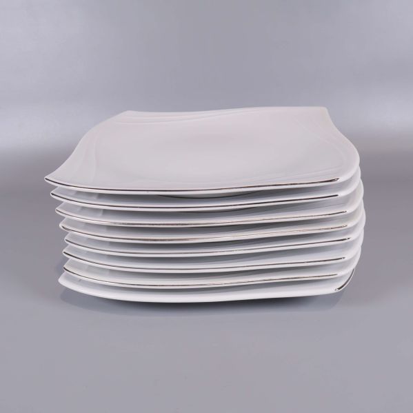 Sida av staplade vita fyrkantiga tallrikar mot grå bakgrund