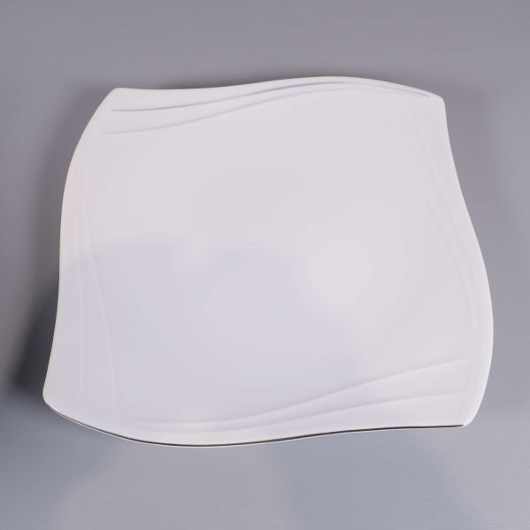 En vit fyrkantig tallrik med vågformad yta sedd ovanifrån