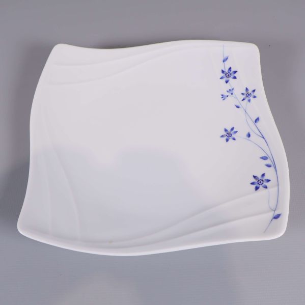 Närbild på assiett med blå blommor och vågig kant