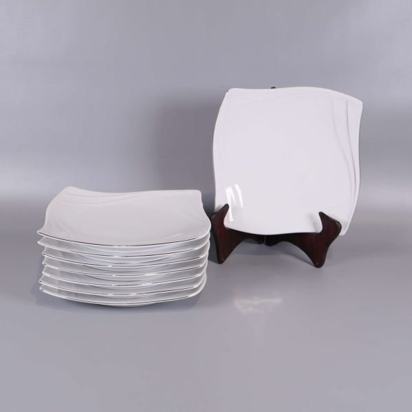 Åtta vita vågformade assietter, en på ställ