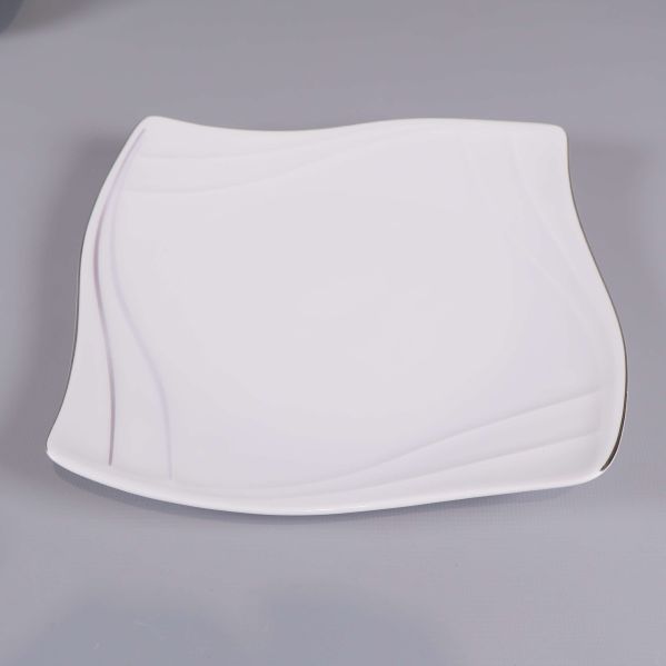 Närbild på en vit fyrkantig assiett med svängda kanter