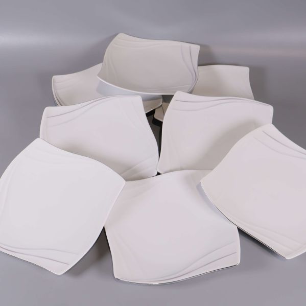 Åtta vita assietter med böjda kanter utspridda