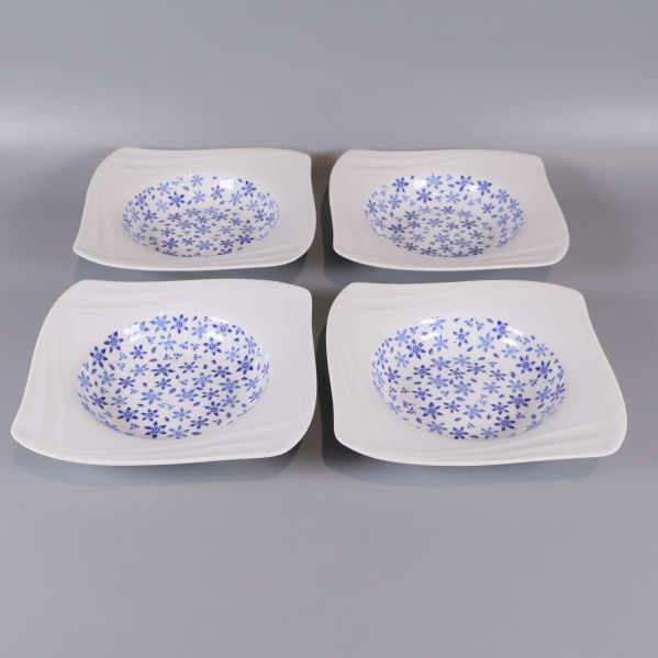 Fyra blommiga djupa tallrikar arrangerade på rad