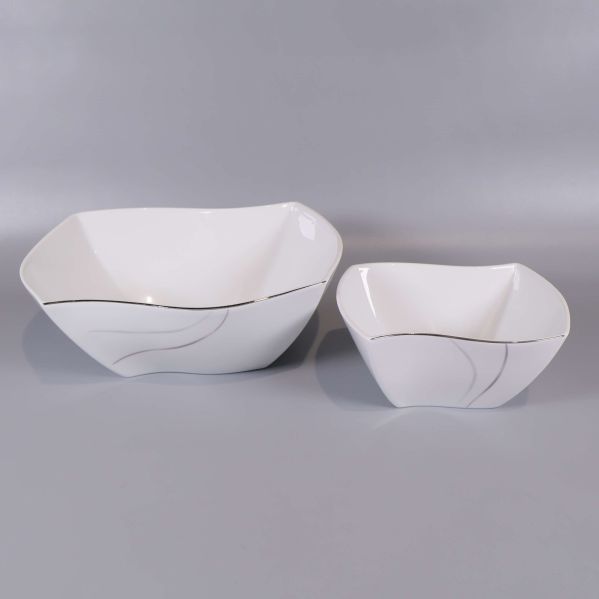Två fyrkantiga vita skålar med silvriga detaljer