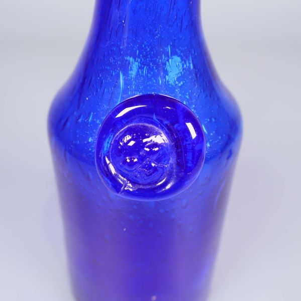 Detaljbild på glasflaskans emblem med ansikte