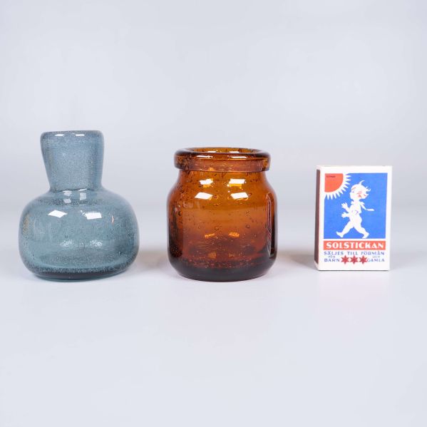 Två små glasvaser jämte tändsticksask för storleksreferens