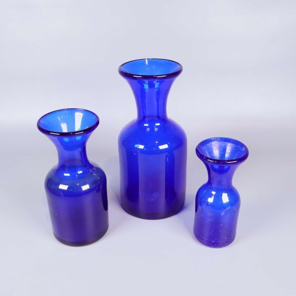 Tre blå glasvaser i olika storlekar på ljus bakgrund