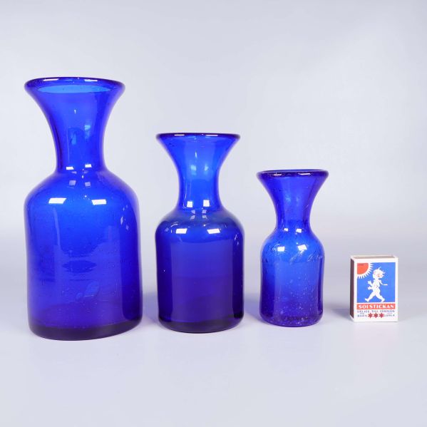 Blå glasvaser i olika storlekar bredvid tändsticksask