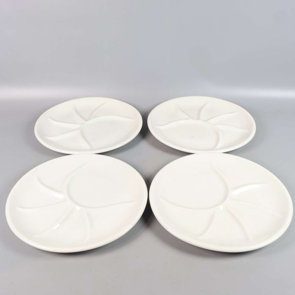 Fyra fackindelade vita tallrikar utspridda på bord