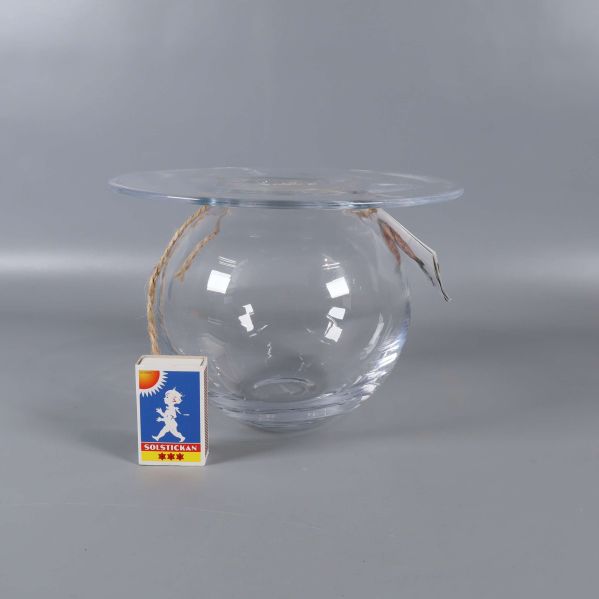 Glasvas visad framifrån bredvid tändsticksask för storleksreferens