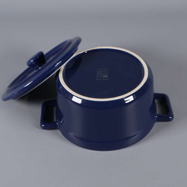 Gryta upp och ned med locket bredvid, bottens märkning synlig