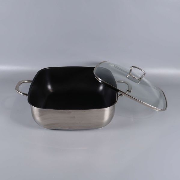 Öppen gryta med glaslocket lutat bredvid