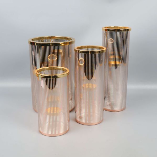 Fyra cylinderformade ljuslyktor med guldiga detaljer