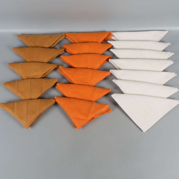 Tre rader vikta servetter i vitt, orange och brunt