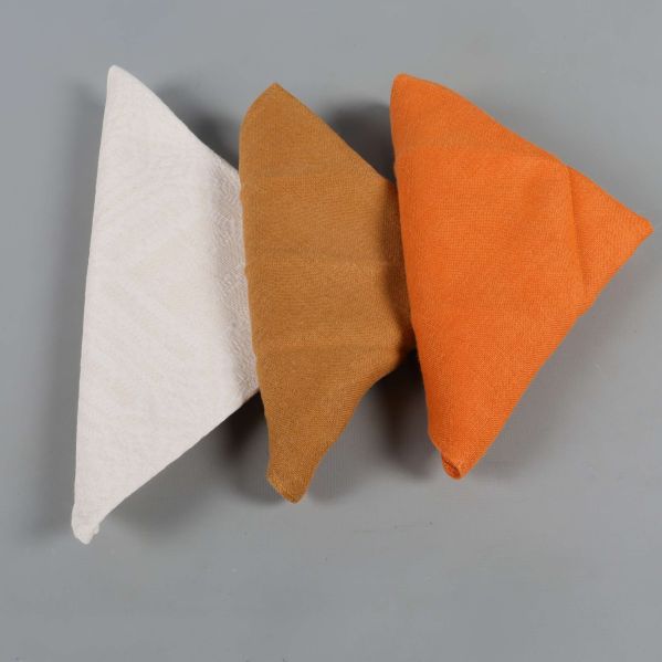 Närbild på tre vikta servetter i olika färger