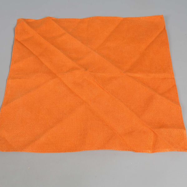 Utfälld orange tygservett på grå bakgrund
