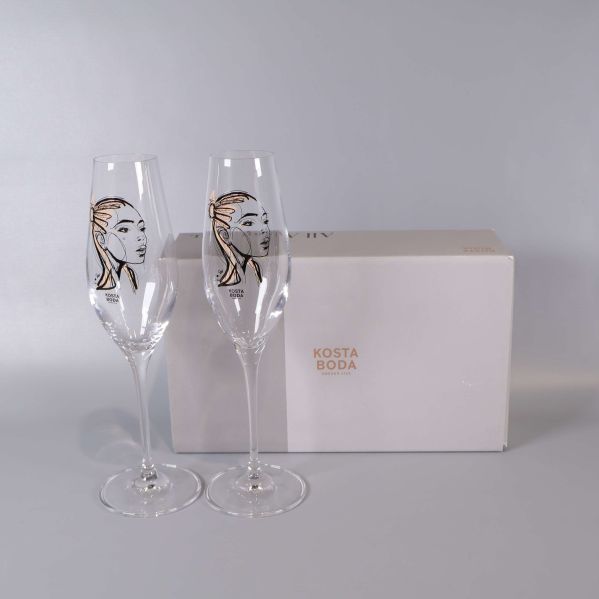 Två champagneglas med ansiktsmotiv och Kosta Boda kartong