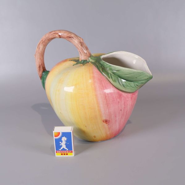 Keramikkanna i fruktform bredvid tändsticksask för storleksjämförelse