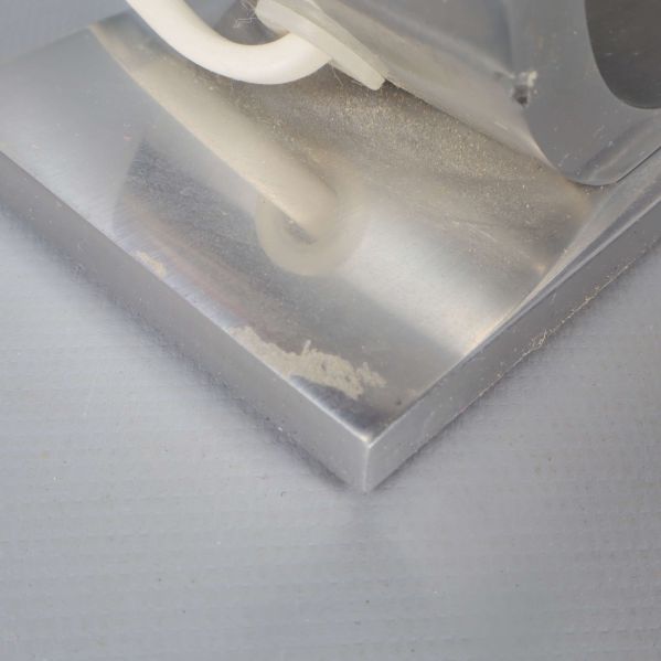 Närbild på lampfot i metall med lätt ytslitage