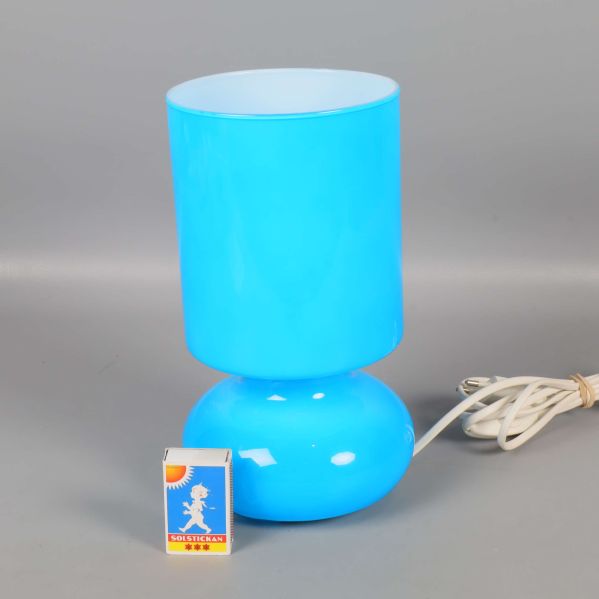 Blå bordslampa bredvid tändsticksask för storleksjämförelse