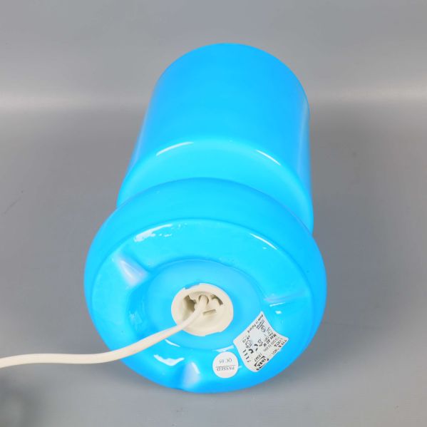 Nederdel av blå bordslampa med vit sladd och etikett