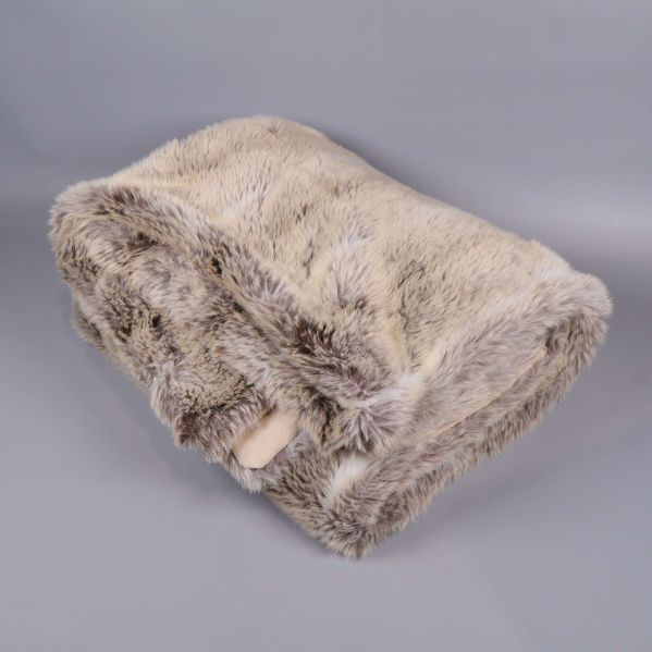 Hopvikt beige och grå fuskpälspläd mot ljus bakgrund