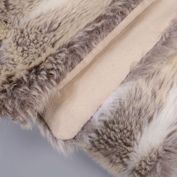 Närbild på plädens kant och baksida i beige textil