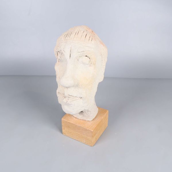 Skulpturhuvud på träbas från sned vinkel