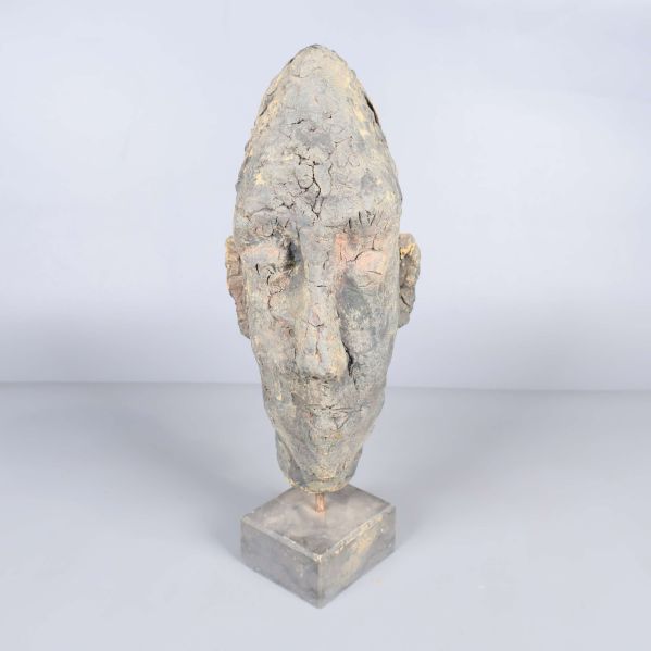 Huvudformad skulptur på kubformad fot sedd framifrån