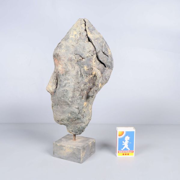 Sidosikt av huvudformad skulptur med tändsticksask bredvid