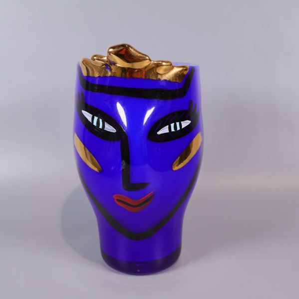 Framsida av blå glasvas med ansiktsmotiv och gulddetaljer