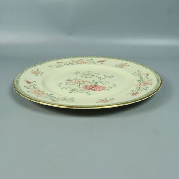 Blommig tallrik sedd i vinkel på grå bakgrund