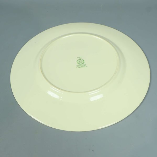 Baksidan av tallrik i gräddvitt med grön stämpel