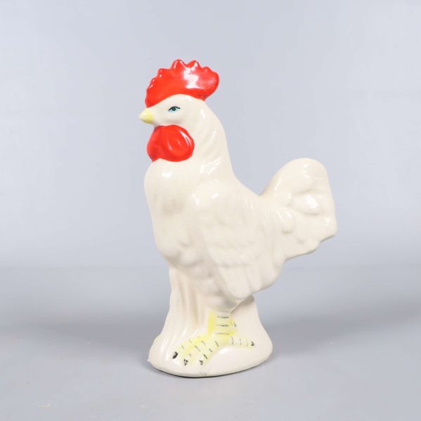 Keramisk tuppfigur sedd snett framifrån med röd kam