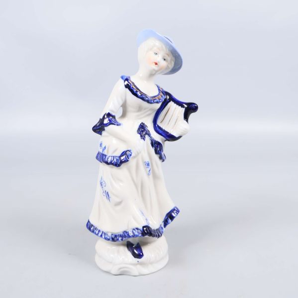 Porslinsfigur i blått och vitt med harpa och hatt