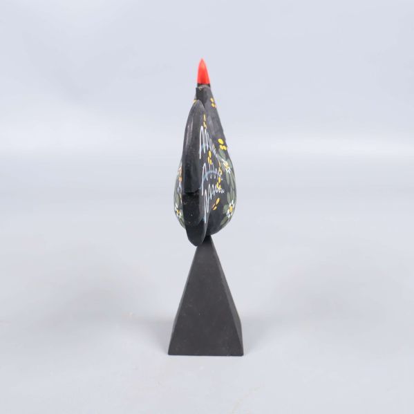 Smalt perspektiv av tuppen har röd kam och svart kropp