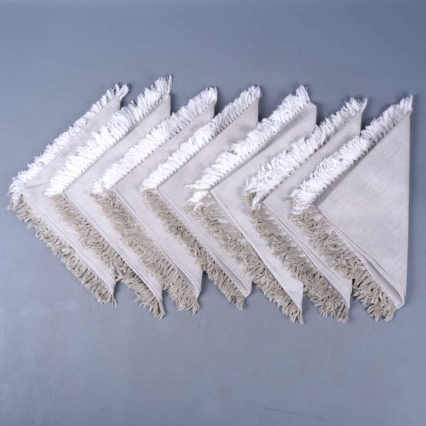 Åtta beige servetter med fransar upplagda i rad