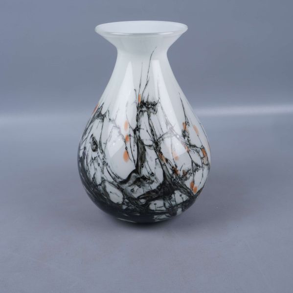 Baksidan av glasvas med svart och orange marmormönster synlig